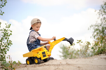 Child, little boy have fun with toy excavator and dumper in the sand. Carefree childhood. - Powered by Adobe