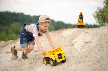 Child, little boy have fun with toy excavator and dumper in the sand. Carefree childhood. © Jacek
