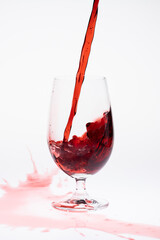 Red wine being poured into wine glass on white background