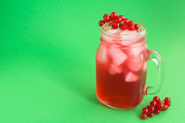 Cold lemonade or cocktail with red currants  in the glass  on the green background. Closeup. Copy space.