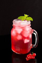 Cold lemonade or cocktail with red currants  in the glass  on the black  background. Closeup. Location vertical.