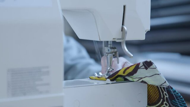 Female sewing together face mask and other PPE on a sewing machine