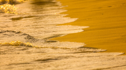 Water on the sandy shore at sunset.