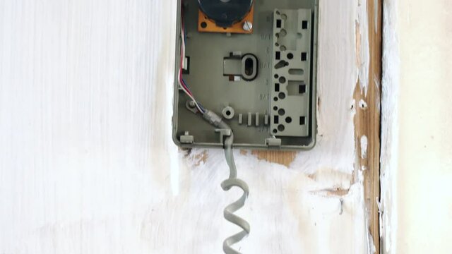 Open intercom broken box with hanging dusted handset, old defective interphone in abandoned house, ancient surveillance security system, retro electronic concept