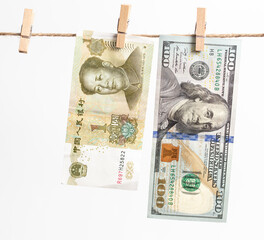Chinese yuan and American dollars hang on a rope on a white background.