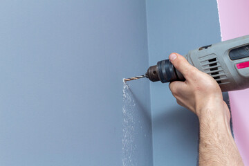 Drilling a gray wall with a drill close-up