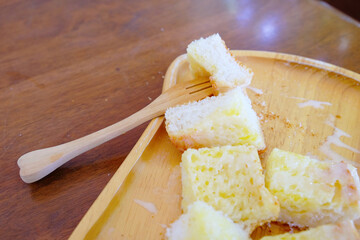 Wood fork stabbed on baked bread with butter and sweetened condensed milk in wooden plate