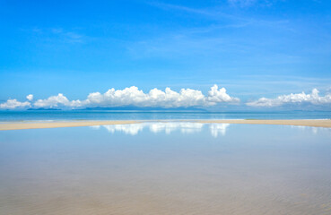 The beauty of the sky, the sea and the sand, the reflection of the clouds on the water. Summer beach background.