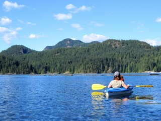 Fototapeta na wymiar A mother kayaking with her young daughter on the ocean on a beautiful sunny day along the sunshine coast outside of Vancouver, British Columbia, Canada