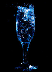 Splashes and drops of water in a glass are isolated on a black background.