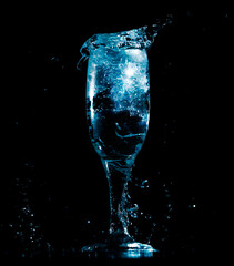 Splashes and drops of water in a glass are isolated on a black background.