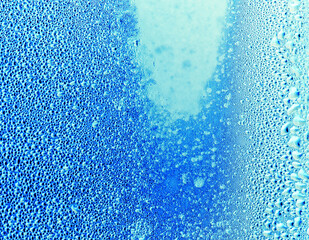 Drops of water on blue glass as an abstract background