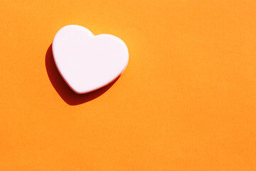 heart shaped cosmetic soap bar on orange background