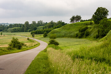 Fototapeta na wymiar Picturesque green landscape view of road winding in grassy hills area. Krasnystaw, Lubelszczyzna, Poland, Europe.