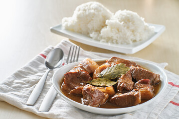 filipino pork adobo in bowl with rice in background