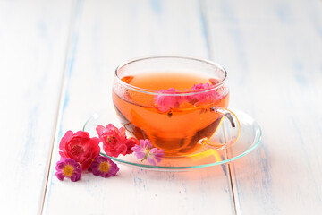 Flower tea in a glass cup on the white table.
