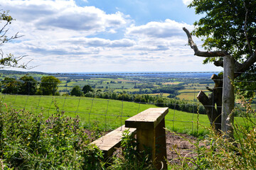 A view of a green Yorkshire wolds valley with a classic walking stile and fence in the foreground 