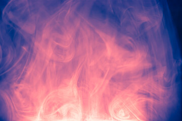 Obraz premium Clouds of colored flowing smoke on a dark background.