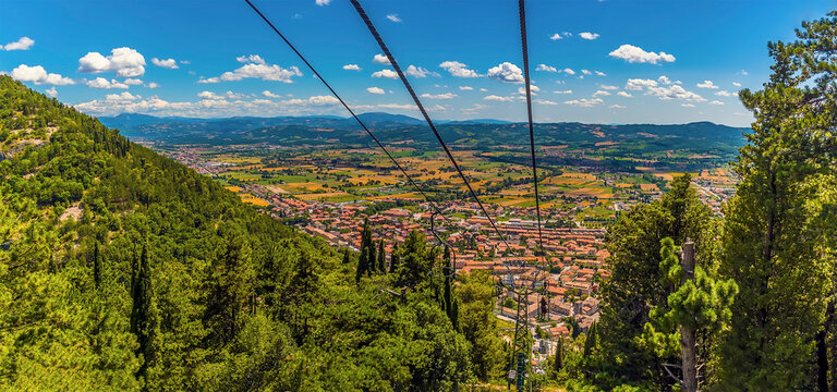A panorama view down the Colle Eletto cable car from the top of Mount Ingino over the cathedral city of Gubbio, Italy towards the Apennine mountains in summer