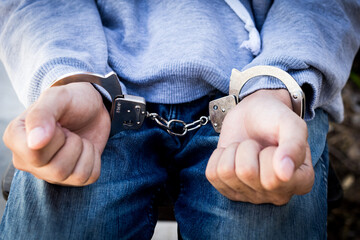 Close up prisoner hands in handcuffs. Arrested man in handcuffed hands.