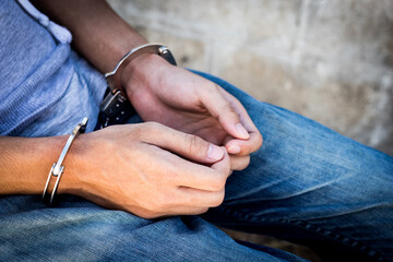 Close up prisoner hands in handcuffs. Arrested man in handcuffed hands.