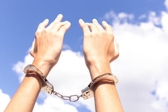 Close up two hands in handcuffs and put your hands up for freedom meaning with blue sky at background. freedom concept.