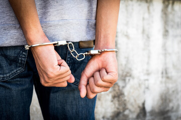 Close up hands tied up handcuffs in behind his body. Arrested man handcuffed hands at the back.