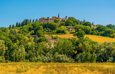 Fototapeta na wymiar The hill top village of Collazzone near Todi, Italy peeks out above the trees in the summertime