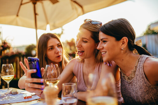 Three young woman at restaurant looking at mobile phone