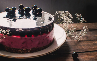 Cheesecake mousse cake with black currant. Delicious cake with berries on a wooden table.