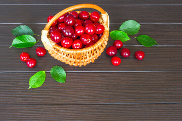 ripe cherries in a wicker basket on a wooden background close-up. background with cherry berries and green leaves. cherries and copy space. cherries in the basket and a copy of the space.