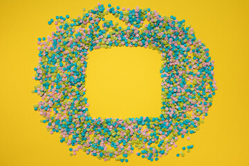 colorful confetti creating a square frame on a yellow background