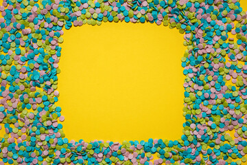 colorful confetti creating a square frame on a yellow background