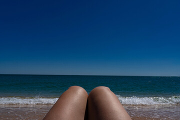 tanned female legs against the background of the azure sea