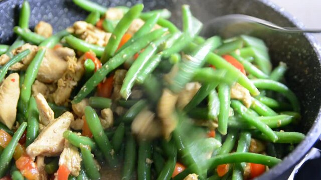 Sprinkling fresh green bean pods over a delicious chicken tikka masala with Indian spices