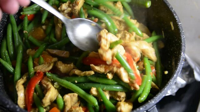 Sprinkling fresh green bean pods over a delicious chicken tikka masala with Indian spices