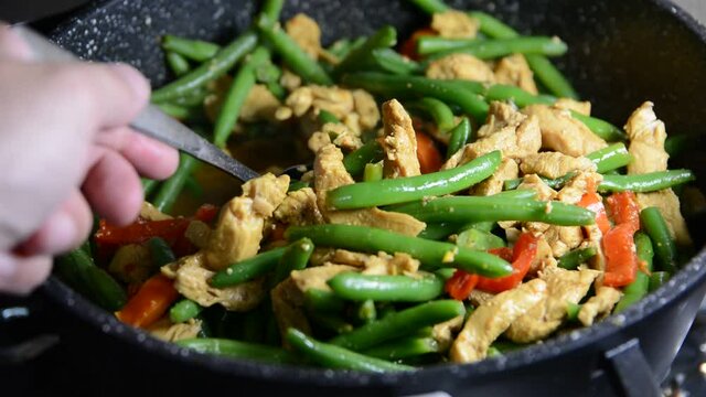 Sprinkling fresh green bean pods over a delicious chicken tikka masala with Indian spices