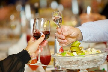 A glass of alcoholic beverage in the hands of an adult.