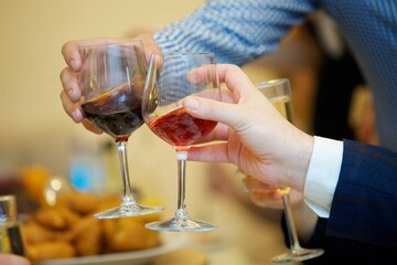 A glass of alcoholic beverage in the hands of an adult.