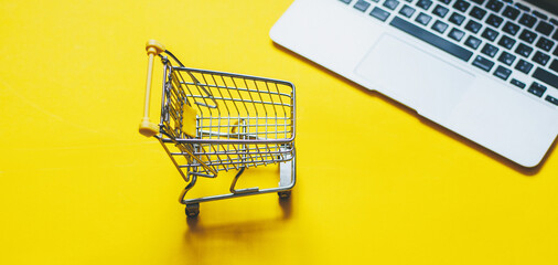 On a yellow background, shopping cart and credit cards, online shopping concept. Online shopping, e-commerce, internet banking, spending money, work from home concept