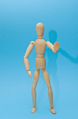 wooden figurine of a man on a colored background, holds an inscription, a coin