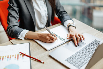 Girl works on a laptop in the workplace. Successful business woman creates a startup and makes...