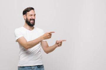 Cute young man smiles, shows his fingers to the right