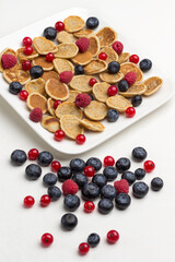 Cereal pancakes, raspberries and blueberries in white ceramic plate. Blueberries and red currants