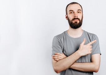 Handsome brunette man with a beard points a finger at a place for advertising on a white background