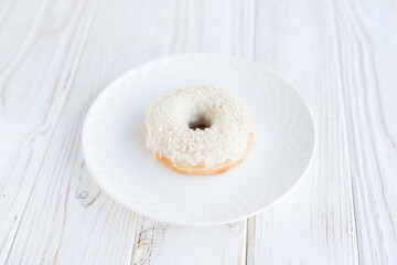 Close-up view of donut on a small white plate with white background. Fresh sweet colorful homemade vanilla donuts on vintage background for birthday or party, top view, with free space for text
