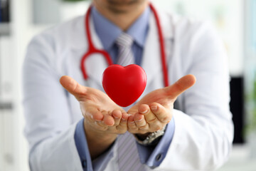 Male medicine doctor hands holding and covering red toy heart - obrazy, fototapety, plakaty