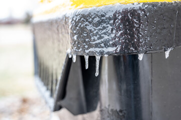 freezing rain starting to form icicles on the lid of a trash bin