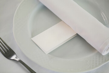 card with the name on the plate on the table with Cutlery, setting for the wedding reception in the restaurant
