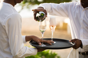 Waiter pouring champagne into glass.